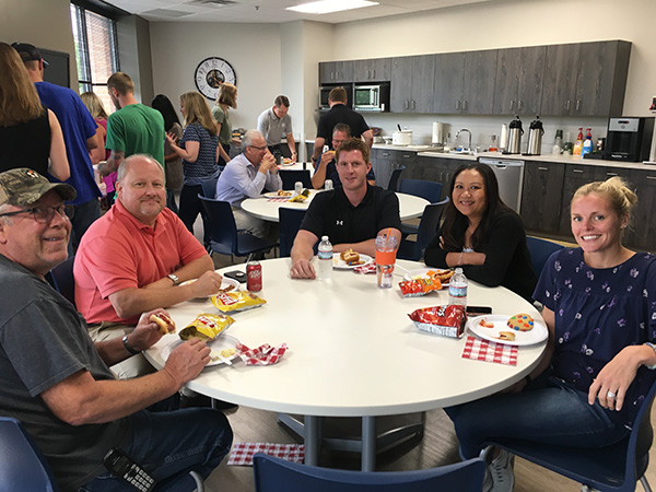 Employees at a team luncheon, sitting at a table with plates and food in front of them.