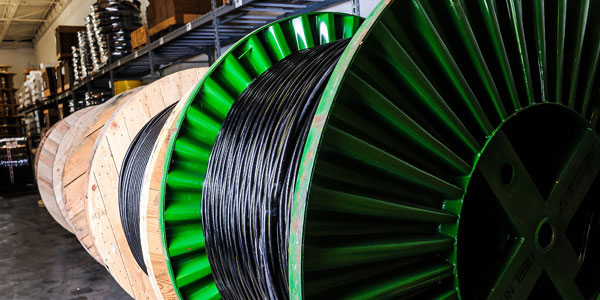 Black medium voltage cable Black medium voltage cable on a large green spool inside a warehouse.